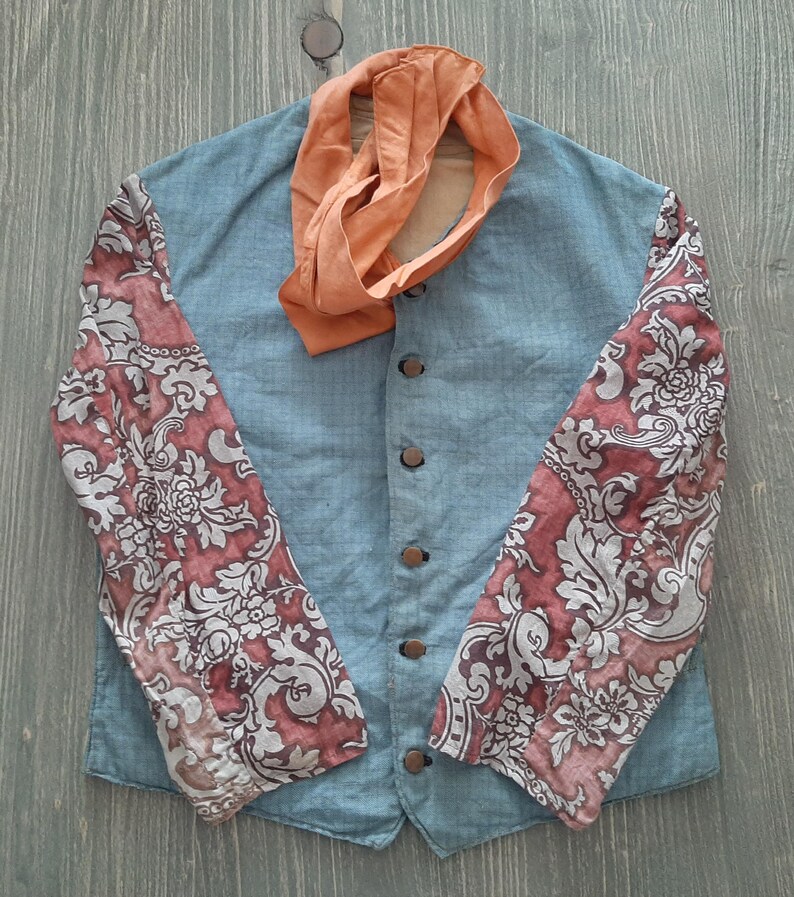 May include: A blue linen jacket with a mandarin collar and floral patterned sleeves. The jacket has five buttons down the front and a matching orange scarf.