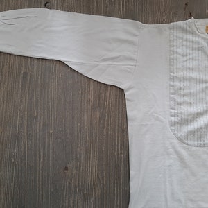 Op de afbeelding: Een wit overhemd met lange mouwen, een knoopsluiting en een klein zakje op de borst. Het zakje heeft een klein, donkerblauw patroon.