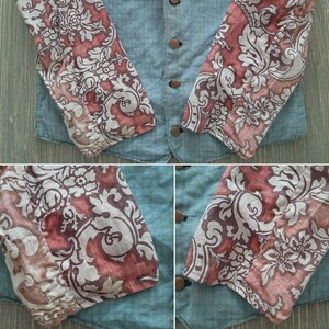 May include: A denim jacket with long sleeves featuring a floral pattern in shades of pink, white, and gray. The sleeves are made of a different fabric than the jacket itself.