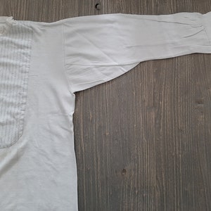 Op de afbeelding: Een wit overhemd met lange mouwen, een knoopsluiting en een decoratief paneel aan de voorkant. Het paneel heeft verticale stiksels.