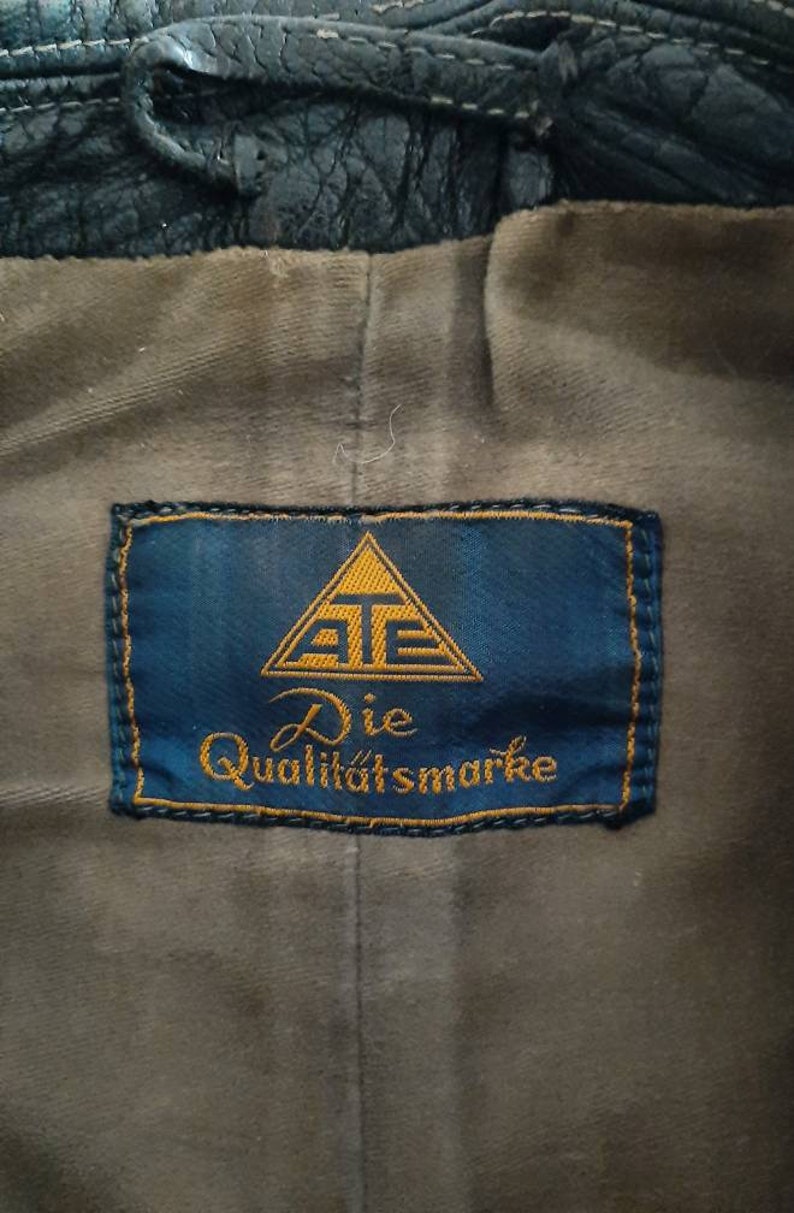 May include: A blue label with a gold triangle containing the letters "AT" and the text "Die Qualit&auml;tsmarke".