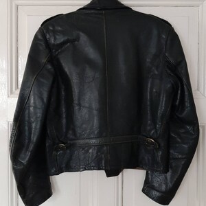 May include: A dark green leather jacket with a zipper closure and a belt at the waist.
