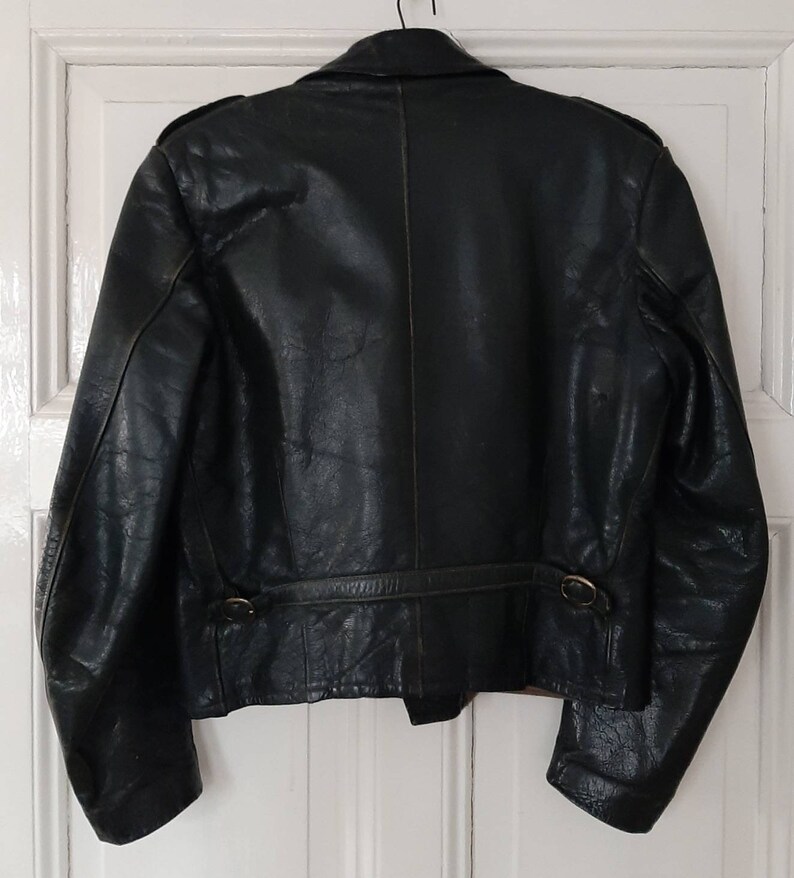 May include: A dark green leather jacket with a zipper closure and a belt at the waist.