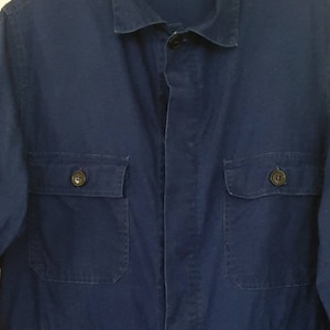 May include: A dark blue workwear jumpsuit with a button-up front and two large pockets on the chest.