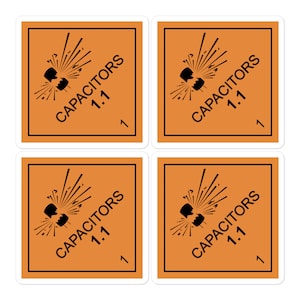 May include: Four orange square warning labels with black borders and black text. Each label has a black illustration of a capacitor exploding with sparks. The text on each label reads "CAPACITORS 1.1".