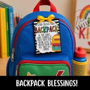 May include: A blue backpack with a green front pocket, a red zipper, and a yellow mesh side pocket. A rectangular tag with a yellow bow is attached, featuring black and white stripes and text that reads: Lord Bless This BACKPACK & THE CHILD WHO CARRIES IT. MAY THEY FEEL YOUR LOVE & PROTECTION IN ALL THEY DO. -AMEN.