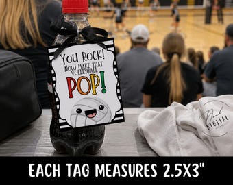 May include: A clear plastic bottle with a red cap and a black ribbon tied around the neck, holding a rectangular white tag with black stripes. The tag features the text "YOU ROCK! NOW MAKE THAT VOLLEYBALL POP!" and a cartoon volleyball, measuring 2.5x3 inches.