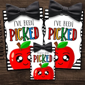 May include: Three printable gift tags with a black and white striped background. The tags feature a red apple with a smiling face and the text "I've Been Picked" and "You've Been Picked".