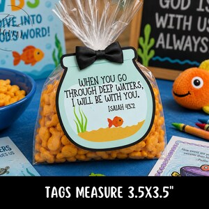 May include: A clear cellophane bag filled with goldfish crackers, topped with a black bow. The tag reads "When you go through deep waters, I will be with you. Isaiah 43:2." The tag measures 3.5 x 3.5 inches.