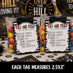 May include: Two cellophane bags filled with colorful candies, each with a black bow and a card that reads "OLD AGE PILLS." The card lists ailments and colors. The text "EACH TAG MEASURES 2.5X3" is at the bottom.