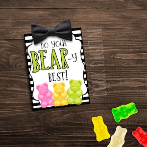 以下が含まれることがあります： 黒い蝶ネクタイと「Do your BEAR-y best!」というテキストが書かれた印刷可能なカード。カードの下部には、ピンクのグミベア1つ、黄色のグミベア1つ、緑のグミベア2つが描かれています。