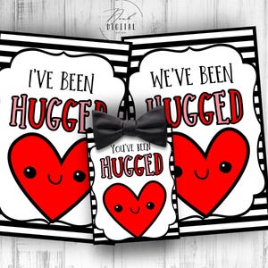 May include: Three printable Valentine's Day cards with black and white stripes and a red heart with a smiling face. The text on the cards reads "I've Been Hugged", "We've Been Hugged", and "You've Been Hugged".