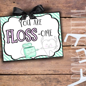 May include: A green and white striped sign with the text "You are floss-ome" in pink and black lettering. A cartoon tooth and a cartoon container of floss are holding a piece of floss between them.