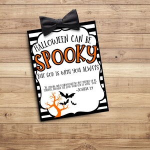 May include: A printable sign with black and white stripes and orange text that reads "Halloween can be spooky but God is with you always." The sign also includes a black bow tie, a black and orange tree, and bats. The text "The strong and courageous do not tremble or be terrified, because the Lord your God is with you." - Joshua 1:9 is also included on the sign.