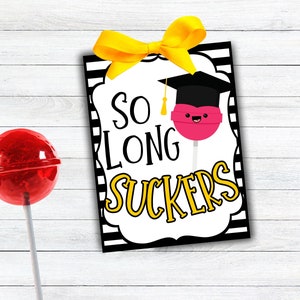 May include: A graduation party favor tag with a black and white striped background. The tag features a pink lollipop with a graduation cap and the text "So Long Suckers" in yellow letters.