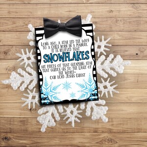 May include: A black and white striped card with a black bow tie on top. The card has a white background with blue snowflakes and the text "LONG AGO, A STAR LED THE WAY TO A CHILD BORN IN A MANGER. IT IS BELIEVED THAT SNOWFLAKES ARE PIECES OF THAT GLEAMING STAR THAT GUIDES US TO THE LIGHT OF THE WORLD- OUR LORD JESUS CHRIST".