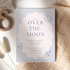 May include: A baby shower invitation with the text "Over the Moon" in a soft blue and pink color scheme. The invitation includes details such as the date, time, and location, along with the name Eleanor Jones. Decorative elements include stars and a crescent moon.