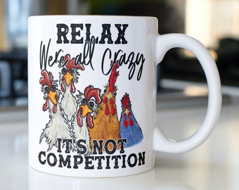 May include: White ceramic mug with a black and white graphic of chickens and the text "Relax We're all Crazy It's not Competition".