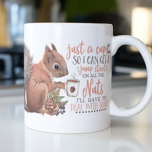 May include: White ceramic mug with a brown squirrel holding a cup of coffee. The mug has the text "just a cup so I can get a jump start on all the nuts I'll have to deal with today".