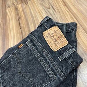 Może przedstawiać: Czarne dżinsy z denimu z brązową naszywką Levi Strauss & Co. z napisem "517" i "W32 L30".