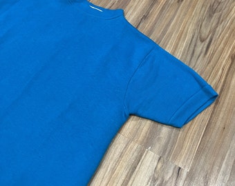 May include: A bright blue short-sleeved t-shirt made of a soft, comfortable fabric. The shirt has a crew neck and a relaxed fit.
