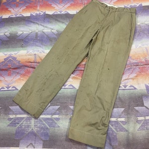 May include: A pair of khaki-colored pants with a straight leg and a slightly faded appearance. The pants have a button fly and belt loops.