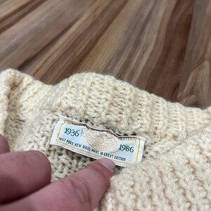 May include: A white knitted sweater with a green label that reads "1936 100% PURE NEW WOOL MADE IN GREAT BRITAIN 1986".