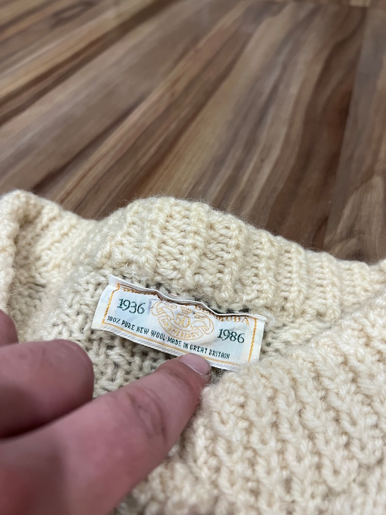 May include: A white knitted sweater with a green label that reads "1936 100% PURE NEW WOOL MADE IN GREAT BRITAIN 1986".