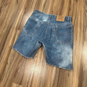 May include: Blue denim shorts with frayed edges and a brown leather patch with the text "Levi's®" and "Original" on the back.