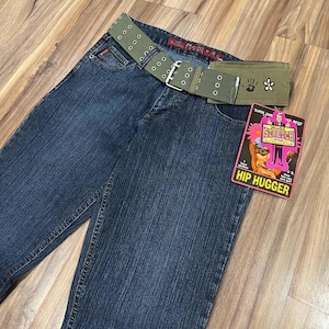 May include: Dark blue denim jeans with a green canvas belt and a small green canvas wallet with a handprint and flower design. The jeans have a label that says "Super Stretch" and "Hip Hugger".