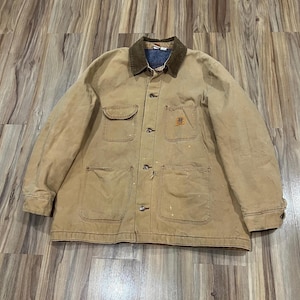 May include: A tan work jacket with a brown corduroy collar and multiple pockets. The jacket has a button-up front and a small logo on the chest pocket. The jacket appears worn, with paint splatters and signs of wear.