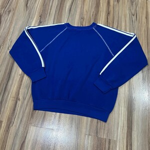 May include: A royal blue sweatshirt with white stripes on the sleeves. The sweatshirt has a crew neck and a relaxed fit.