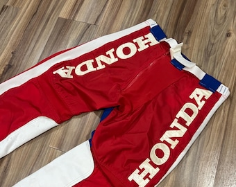 May include: Red, white, and blue motocross pants with "HONDA" printed in white on both legs.