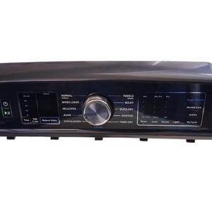 May include: A black control panel for a GE Profile appliance. It features a central dial and several touch-sensitive buttons with text labels such as "Normal", "Delicates", "Quick Dry", and "Steam". The panel also includes a digital display.