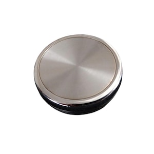 May include: A round, silver-colored object with a brushed metal finish. The object has a circular design with a shiny, reflective surface. The item appears to be a lid or a cover, possibly for a container or a similar product.