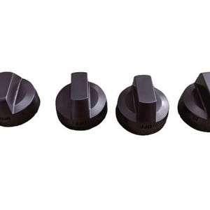 May include: Four dark gray stove knobs with a rounded base and a rectangular handle. The knobs are labeled with text such as "MED" and "OFF". The knobs are arranged horizontally against a white background.