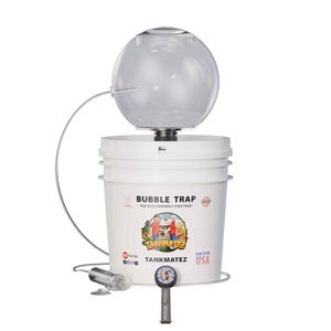 May include: A white bucket with a clear, spherical top, labeled "BUBBLE TRAP." The design includes a metal arm and a small, clear tube. The bucket has a graphic of two people and the text "TANKMATEZ" and "MADE IN THE USA."