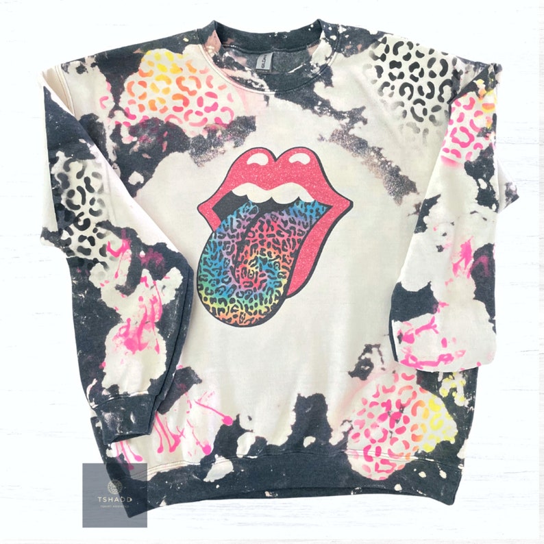K&ouml;nnte beinhalten: Schwarz-wei&szlig;es Batik-Sweatshirt mit einem Regenbogen-Leoparden-Zungen-Motiv. Die Zunge ist rot mit wei&szlig;em Rand und das Motiv erinnert an eine ber&uuml;hmte Rockband.