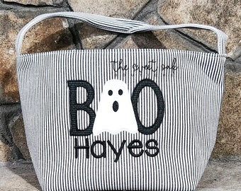 May include: A black and white striped fabric tote bag with a ghost and the text "BOO Hayes" embroidered on the front. The text "The Sweet Spot Boutique" is also embroidered on the bag.