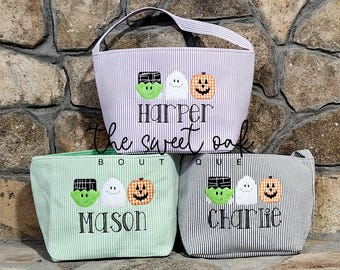 May include: Three striped fabric Halloween treat bags with embroidered ghosts, pumpkins, and monsters. The bags are personalised with the names "Harper", "Mason", and "Charlie".