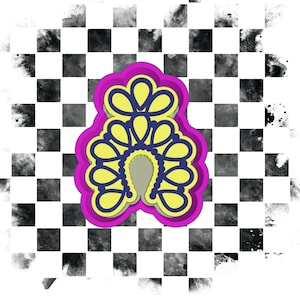 Op de afbeelding: Een koekjesvorm in de vorm van een decoratief ontwerp. De uitsteker heeft een geel en blauw ontwerp met een roze omtrek. De achtergrond is een zwart-wit geblokt patroon met inktvlekken.