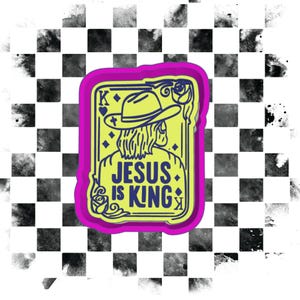 K&ouml;nnte beinhalten: Ein neongr&uuml;ner und violetter Aufkleber mit den Worten "JESUS IS KING". Das Design zeigt eine Illustration einer Person mit Cowboyhut und Spielkarte mit Krone. Der Hintergrund ist ein schwarz-wei&szlig;es Schachbrettmuster.