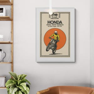 Puede incluir: Un póster enmarcado de un manual de servicio de motocicletas Honda vintage. El póster presenta una ilustración de una motocicleta con un piloto en amarillo, sobre un círculo naranja. Se muestra el texto "HONDA" y "CLYMER PUBLICATIONS".
