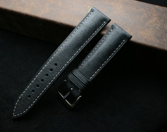 May include: Two black leather watch straps with white stitching. One strap has a buckle and the other has holes for a watch pin.