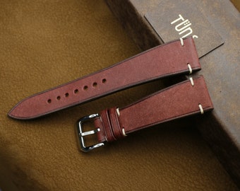 May include: Two brown leather watch straps with white stitching and a silver buckle.