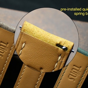 Peut inclure: Gros plan sur un bracelet de montre en cuir beige avec des coutures blanches. Le bracelet est dot&eacute; d'une barre &agrave; ressort &agrave; d&eacute;gagement rapide pr&eacute;install&eacute;e. Le bracelet est marqu&eacute; "TUDOR" en lettres dor&eacute;es.
