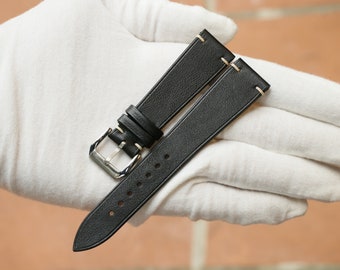 May include: Black leather watch strap with white stitching and a silver buckle.