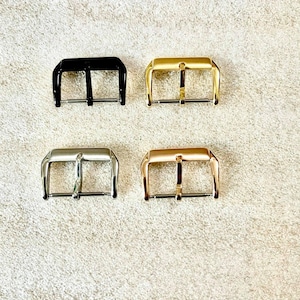 K&ouml;nnte beinhalten: Vier Uhrenarmband-Schlie&szlig;en in verschiedenen Ausf&uuml;hrungen: Schwarz, Silber, Gold und Ros&eacute;gold. Die Schlie&szlig;en sind alle gleich gro&szlig; und haben die gleiche Form mit einem schlichten, klassischen Design.