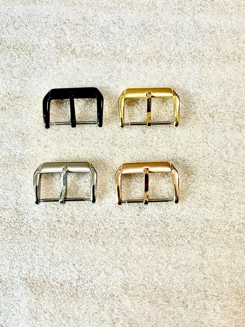 K&ouml;nnte beinhalten: Vier Uhrenarmband-Schlie&szlig;en in verschiedenen Ausf&uuml;hrungen: Schwarz, Silber, Gold und Ros&eacute;gold. Die Schlie&szlig;en sind alle gleich gro&szlig; und haben die gleiche Form mit einem schlichten, klassischen Design.