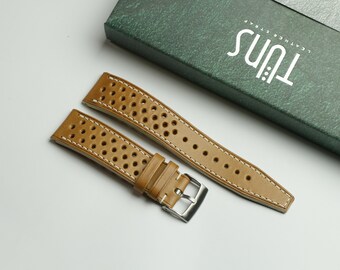 May include: Two brown leather watch straps with white stitching and a perforated pattern. The straps are laid out on a white surface. The text "TULNS Leather Strap" is visible on a green box in the background.